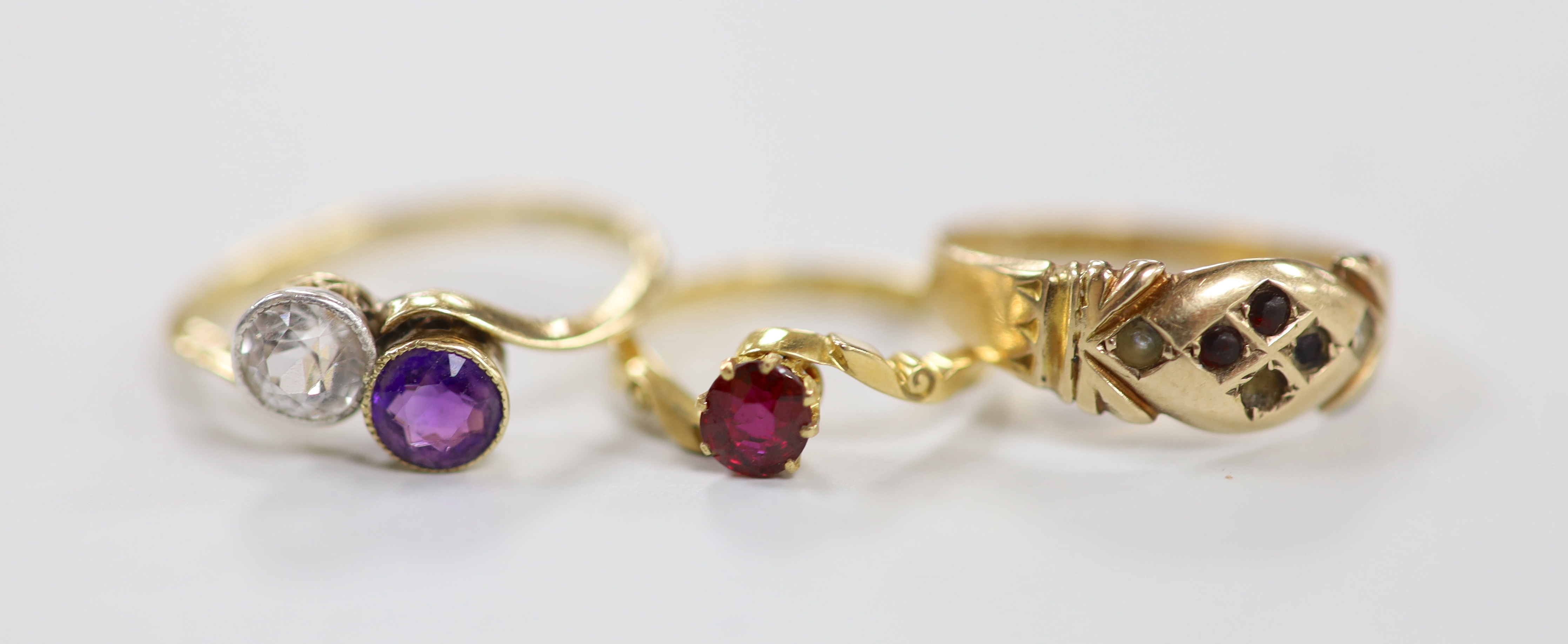 An 18ct, amethyst and simulated diamond set crossover ring, an 18ct and red stone ring, gross weight 4.7 grams and a late Victorian 9ct ring, gross 1.6 grams.